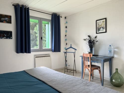 Modern bedroom at La Jument Verte B&B in Southern France with blue curtains, desk, and contemporary décor