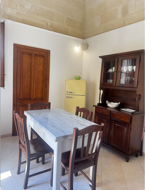 Sala da pranzo di HABITARE Lecce con tavolo in legno, sedie vintage, frigorifero giallo e arredi d'epoca
