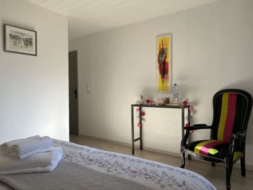 Bedroom at La Jument Verte B&B in Southern France with decorated desk, colorful chair, and white bedding.
