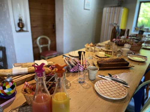 Dining table set for breakfast at La Jument Verte B&B in Southern France, with bread, juice, and plated settings