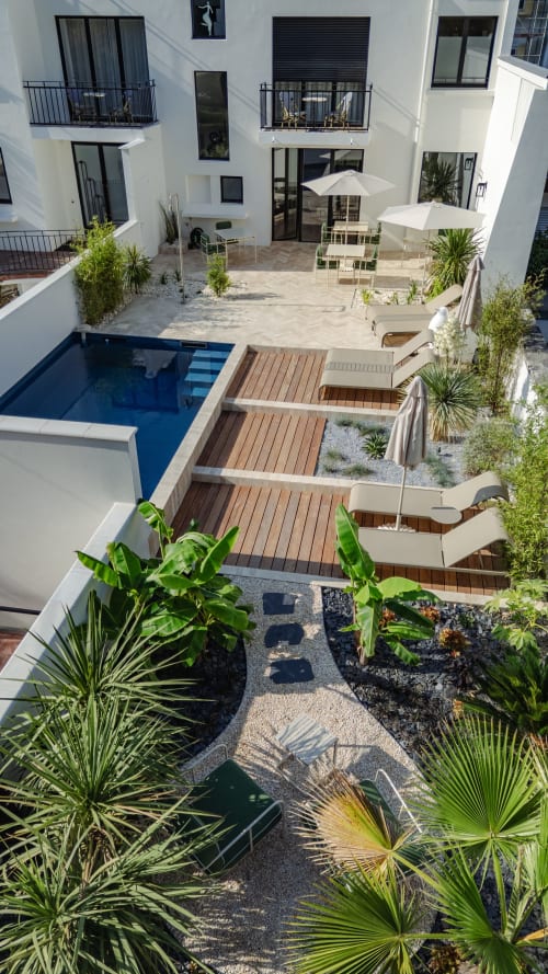 Cour de l'Ode à Pierre à Dax avec piscine, terrasse en bois, parasols blancs et végétation