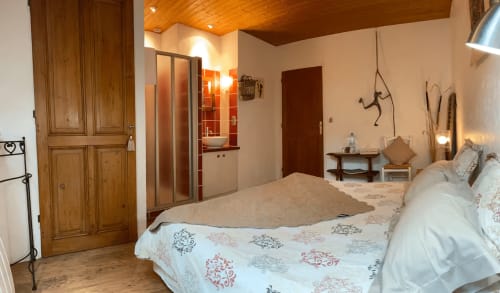 Spacious bedroom at La Jument Verte B&B in Southern France with wooden beams, en-suite bathroom, and rustic decor