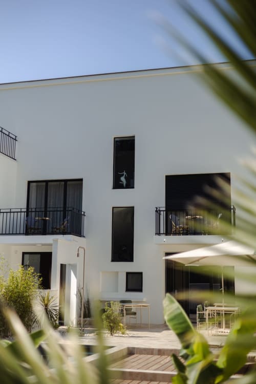 Boutique hôtel L'Ode à Pierre moderne en blanc à Dax, avec fenêtres noires, balcons et terrasse intérieure