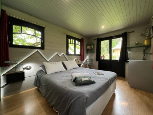 Modern bedroom in La Roulotte apartment at La Jument Verte B&B, Southern France, with mountain-shaped headboard and natural