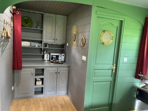 La Roulotte apartment kitchenette at La Jument Verte B&B in Southern France with green door and gray cabinetry