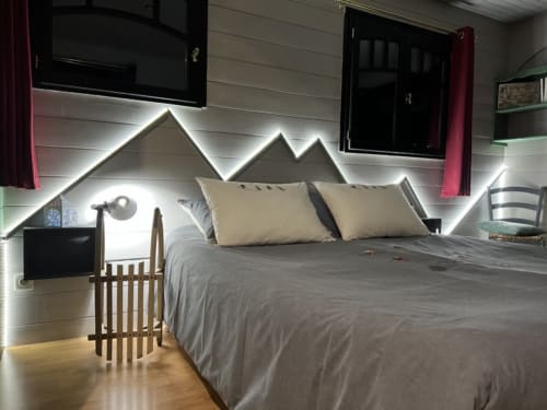 Modern bedroom at La Jument Verte BnB in Southern France featuring mountain-shaped headboard with LED lighting and cream