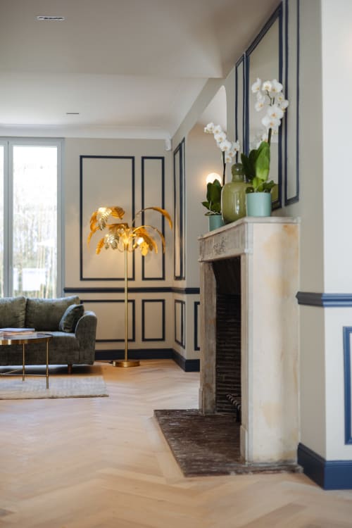 Hall d'entrée élégant à L'Ode à Pierre, Dax avec orchidées blanches, lampadaire doré et portes à panneaux bleu marine