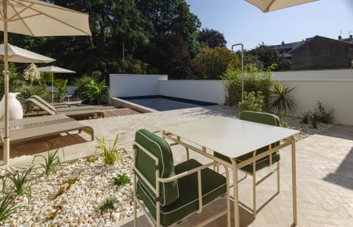 Terrasse moderne de la maison d'hôtes L'Ode à Pierre à Dax avec table de salle à manger, piscine, parasols et verdure luxuriante