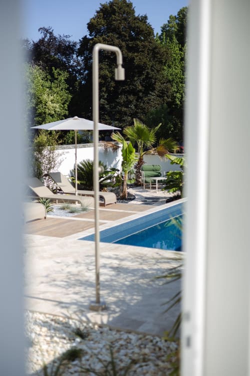 L'espace piscine de prestige de L'Ode à Pierre à Dax, avec parasol, chaises longues et jardin luxuriant