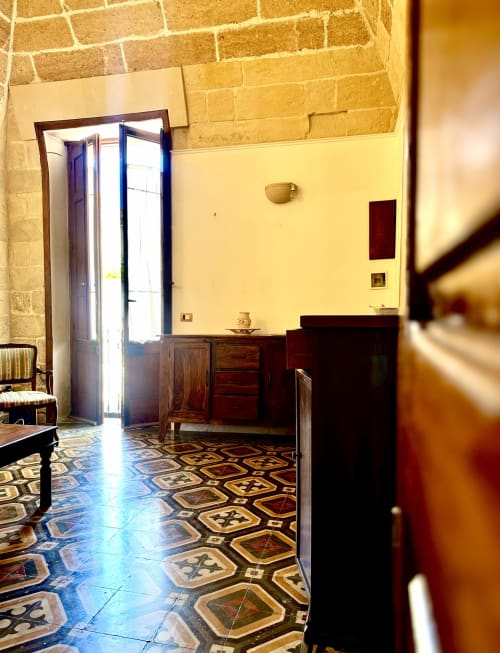 Historic room at HABITARE Lecce with yellow walls, patterned floor tiles, and dark wood furnishings