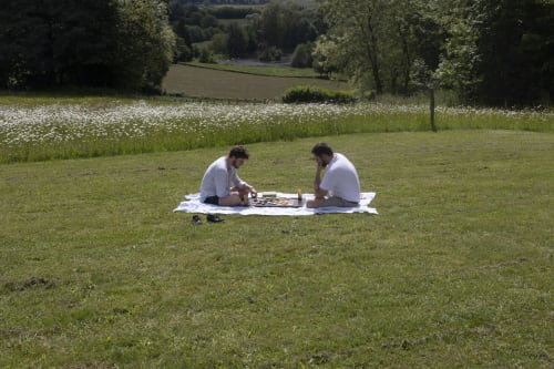 Deux invités pique-niquant sur la pelouse du Château de Vaux Morvan avec vue sur les champs de fleurs sauvages et la campagne à Étang sur