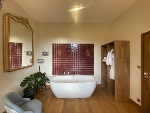 Salle de bain spa luxueuse au Château de Vaux Morvan avec baignoire blanche autoportante, mur d'accent en carreaux bourgogne, miroir doré