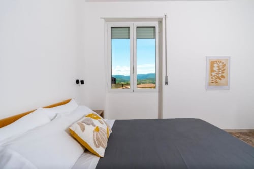Camera luminosa al Domo Cadò B&B di Berchidda con vista sulle montagne dalle porte-finestre
