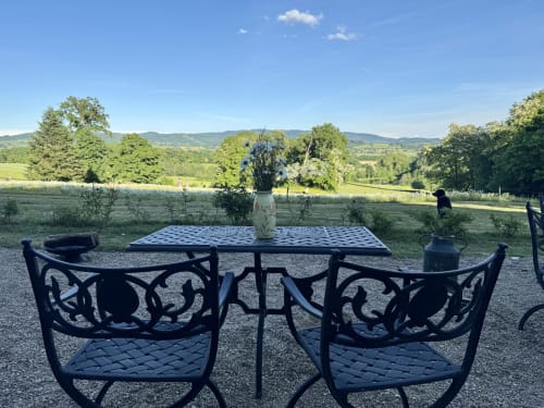 Chaises et table noires ornementées avec fleurs dominant les vallées verdoyantes du Château de Vaux Morvan à Étang sur Arroux