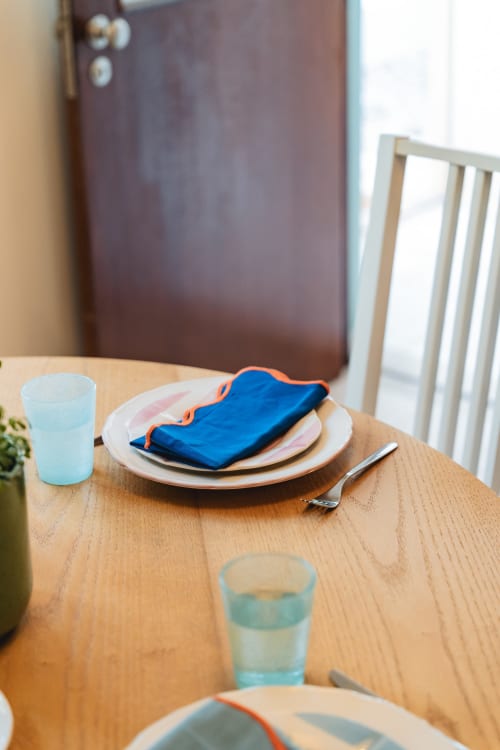 Dining table setting at Arestas e Planetas Cascais Garden House with blue napkin, plates, and water glasses