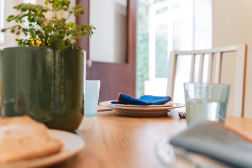 Dining table at Arestas e Planetas Cascais Garden House with place settings, green plant vase, and water glasses overlooking