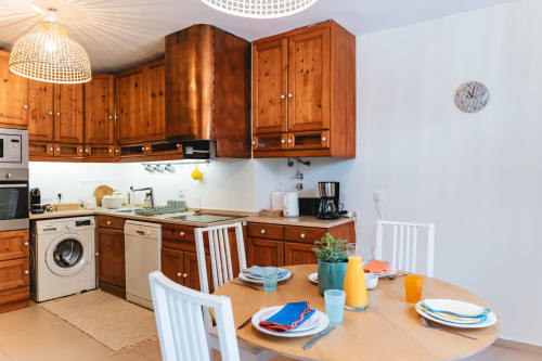 Bright kitchen-dining area in Cascais Garden House with wooden cabinets, set table with blue accents, coffee maker, and