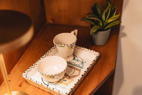Ceramic tea set with hand-drawn llama design on wooden table at Arestas e Planetas, Cascais