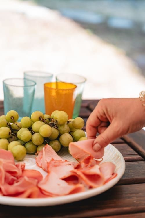 Guest enjoying fresh grapes and cured meats at Arestas e Planetas Cascais Garden House with colorful drinks overlooking