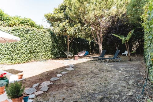 Lush garden patio at Arestas e Planetas in Cascais with lounge chairs, shade trees, and ivy-covered walls