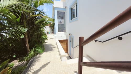 Caminho ensolarado na Vila Vale Guest House em Charneca da Caparica com paredes brancas, palmeiras e corrimãos de madeira