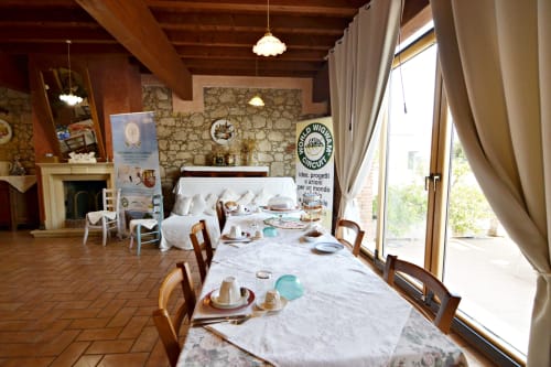 Sala da pranzo rustica a Corte delle Giuggiole con tavoli apparecchiati, muri in pietra, camino e vista sul giardino