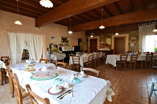 Ampia sala eventi presso la Corte delle Giuggiole con travi in legno, tavoli allestiti, pianoforte e vista sul giardino a Cologna Veneta