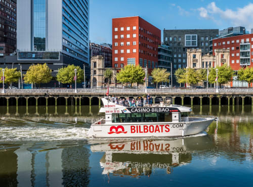 Barco casino Bilboats en el río Nervión con el horizonte de Bilbao, cerca del Palacio Vasco en Laukariz