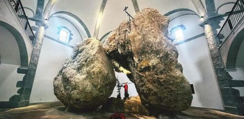 Grandes rocas cubiertas de musgo en galería de arcos de piedra del Palacio Vasco, Laukariz