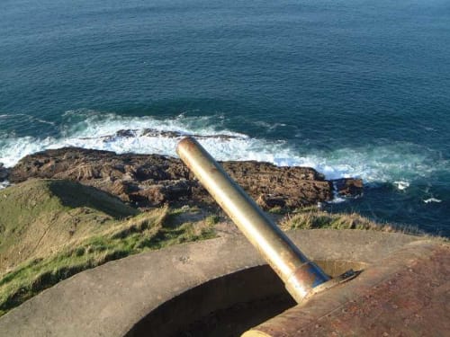 Cañón oxidado con vistas a la costa rocosa vasca y olas en el Palacio Vasco, Laukariz