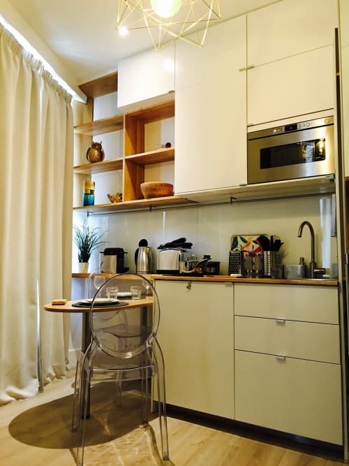 Modern kitchenette in Studio Deluxe at Cocoon Gallery Paris with cream cabinets, wooden shelves, stainless steel appliances,
