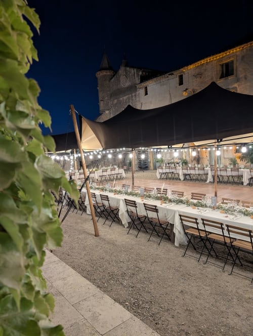 Evening wedding reception at Domaine de Pelican in Gignac with illuminated tent, dining tables, and historic castle tower