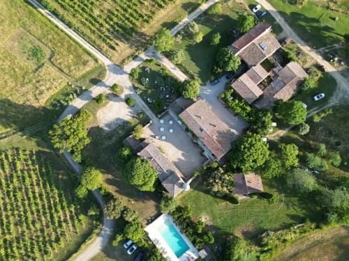 Aerial view of Domaine de Pelican in Gignac, France with rustic stone buildings, courtyard, pool, and surrounding vineyards