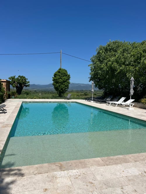 Rectangular swimming pool at Domaine de Pelican in Gignac, France, with loungers, umbrella, and valley views