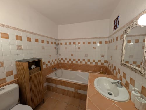 Salle de bain de la chambre Prunelle au Domaine de Pélican, Gignac avec carrelage blanc et terre cuite, baignoire et lavabo