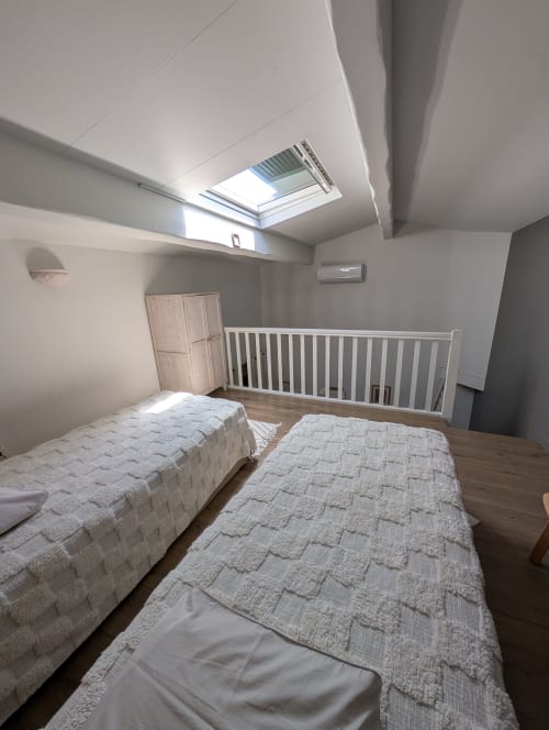 Bright attic bedroom at Domaine de Pelican with twin beds, skylight, and white safety railing in Gignac