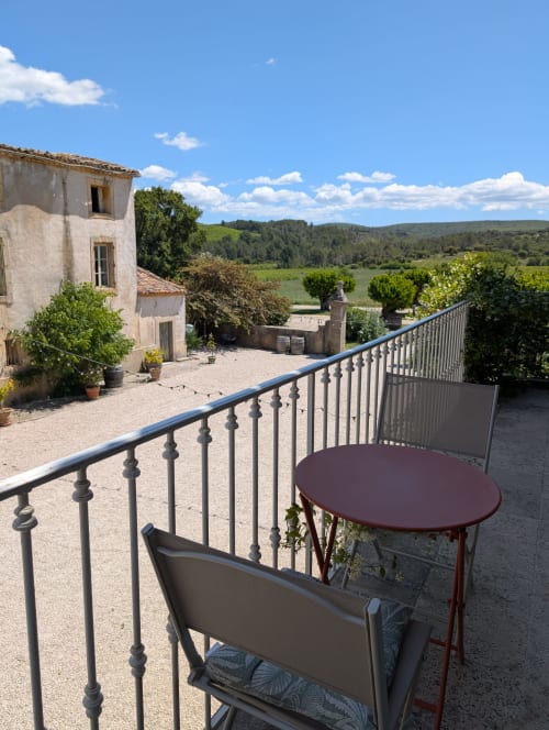 Terrasse avec vue campagne au Domaine du Pélican à Gignac, table, chaise et cour en pierre en contrebas.