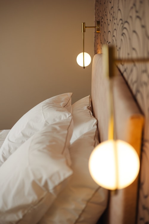 Chambre moderne à la L'Ode à Pierre B&B à Dax avec oreillers blancs et luminaires suspendus en laiton