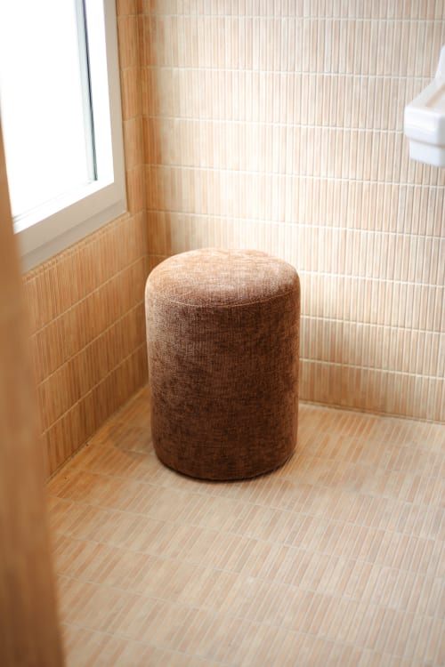 Pouf cylindrique marron dans la salle de bain épurée de l'hôtel-boutique L'Ode à Pierre à Dax