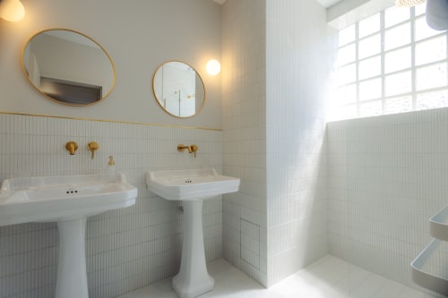 Salle de bain lumineuse à l'Ode à Pierre B&B à Dax avec double vasques sur piédestal, miroirs dorés et carrelage blanc