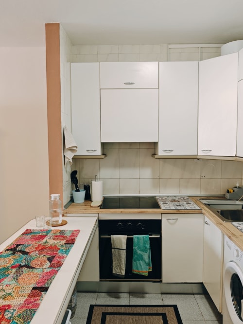 Cocina moderna en apartamento Casa Ormì Corralejo con muebles blancos, horno negro, alfombra colorida y azulejos