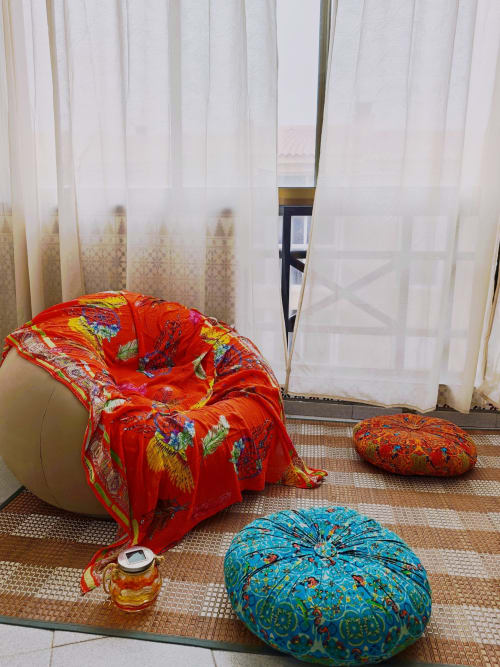 Pufés decorativos coloridos y manta roja bordada en el apartamento Casa Ormì, Corralejo