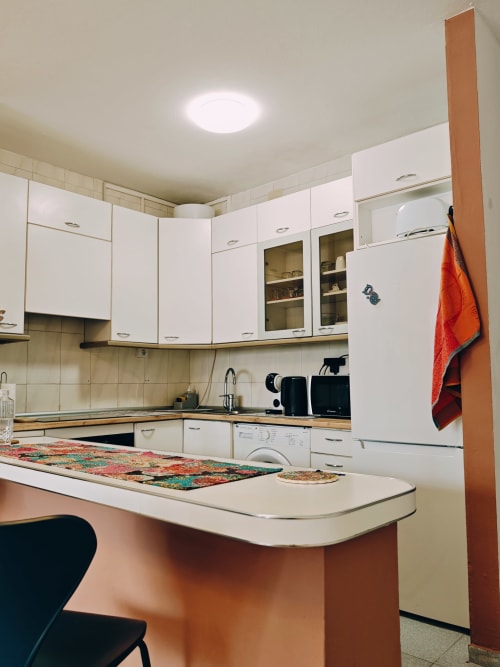 Cocina moderna del apartamento Casa Ormì en Corralejo con muebles blancos, barra isla, electrodomésticos y comedor