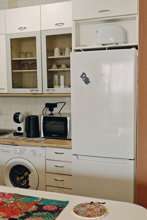Cocina moderna con nevera blanca, armarios, lavadora, microondas y electrodomésticos en Corralejo