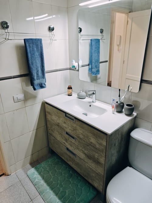 Baño moderno del apartamento Casa Ormì en Corralejo con lavabo blanco, espejo, toallas azules e inodoro