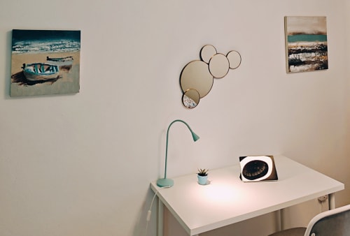 Moderno espacio de trabajo en apartamento de Corralejo con escritorio, lámpara turquesa, planta en maceta, arte temático costero y espejos