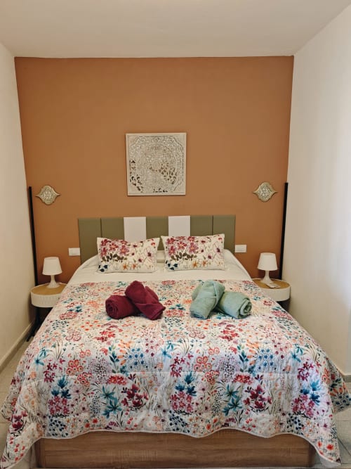 Acogedora habitación en el apartamento Casa Ormì de Corralejo con paredes de barro, ropa de cama floral y comodidades modernas