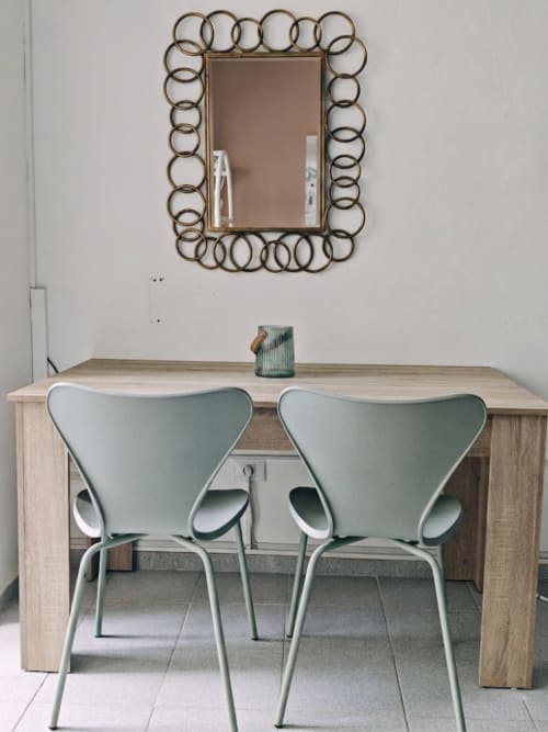 Zona de comedor moderna en apartamento Casa Ormì, Corralejo con mesa de madera clara, sillas verde menta y espejo decorativo