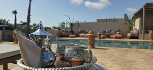 Service de thé marocain au bord de la piscine du Riad Arkaya à Essaouira, avec poterie bleu traditionnel et cour bordée de palmiers