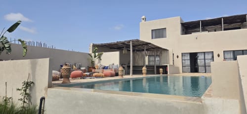 Piscine du riad Arkaya à Essaouira avec eau turquoise, bâtisses blanches, pergola et architecture marocaine